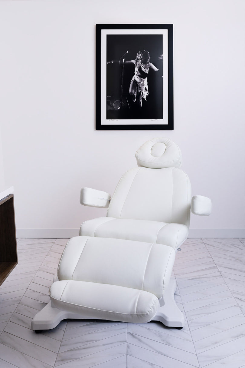 White massage chair in a room with a framed black and white photo on the wall.