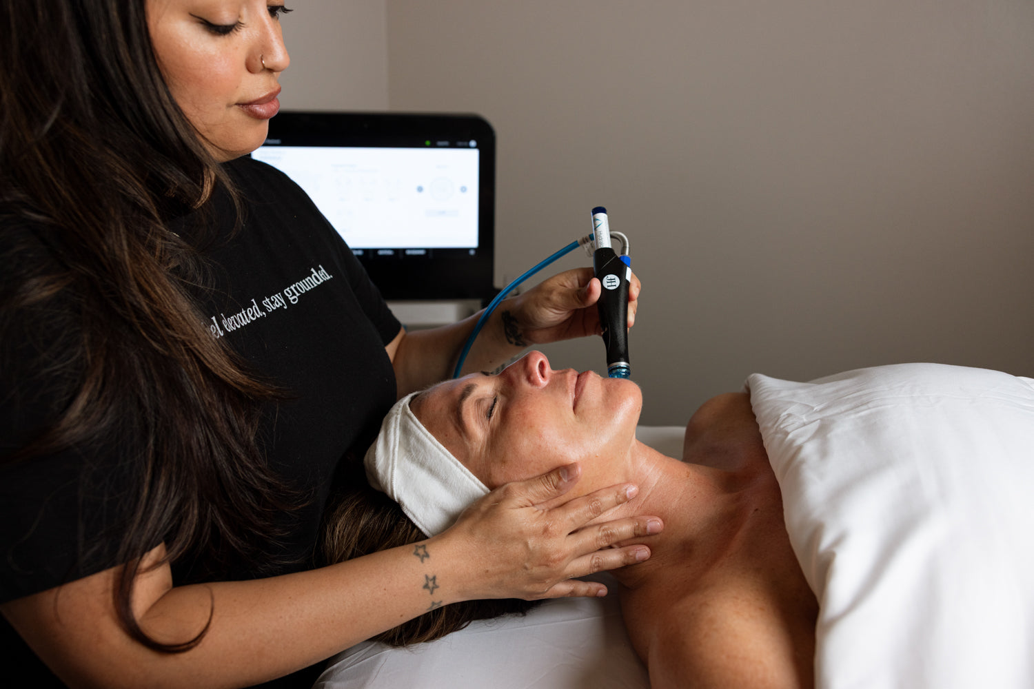 Person receiving a facial treatment with a device from a professional in a clinical setting.