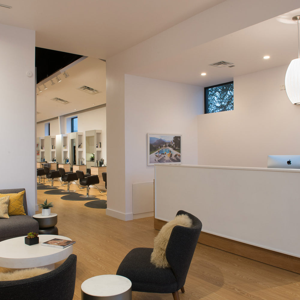 Modern office lobby with reception desk, seating area, and artwork on the walls.