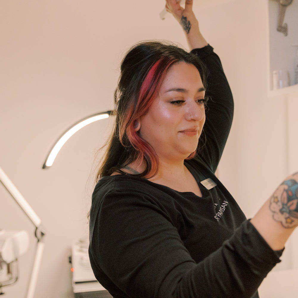 Person with tattoos and colorful hair in a salon setting