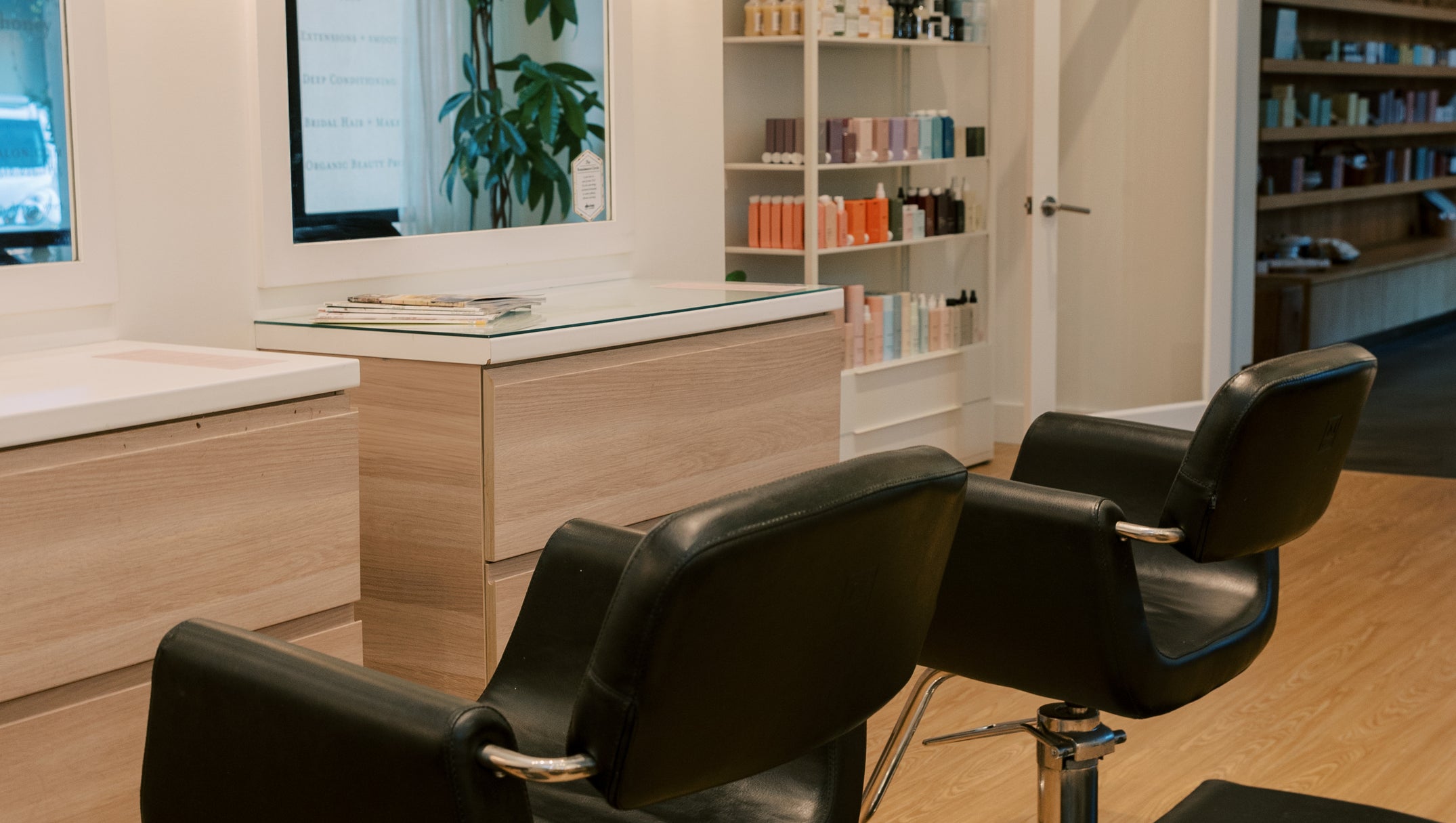 Salon interior with black chairs, mirror, and shelves.