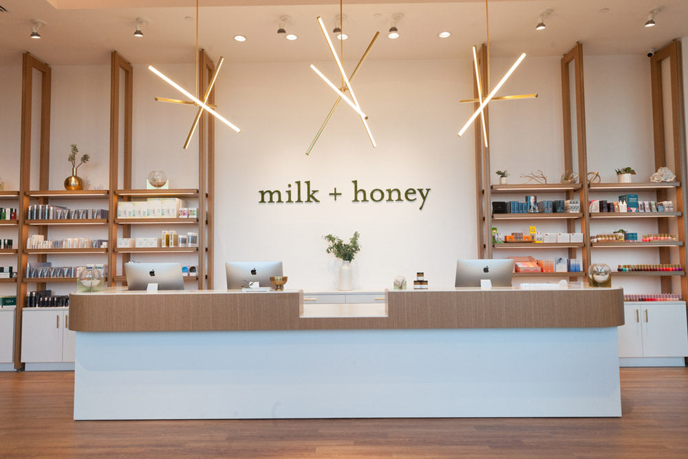 Modern interior of a store named 'milk + honey' with wooden shelves and a reception desk.