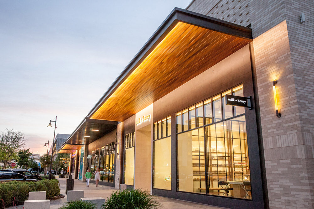 Modern building exterior with wooden canopy and glass windows at dusk.