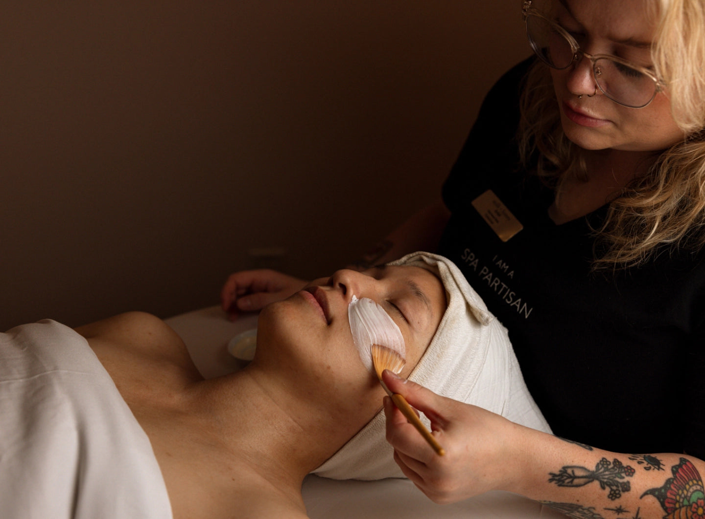 Person receiving a facial treatment with a professional in a spa setting.