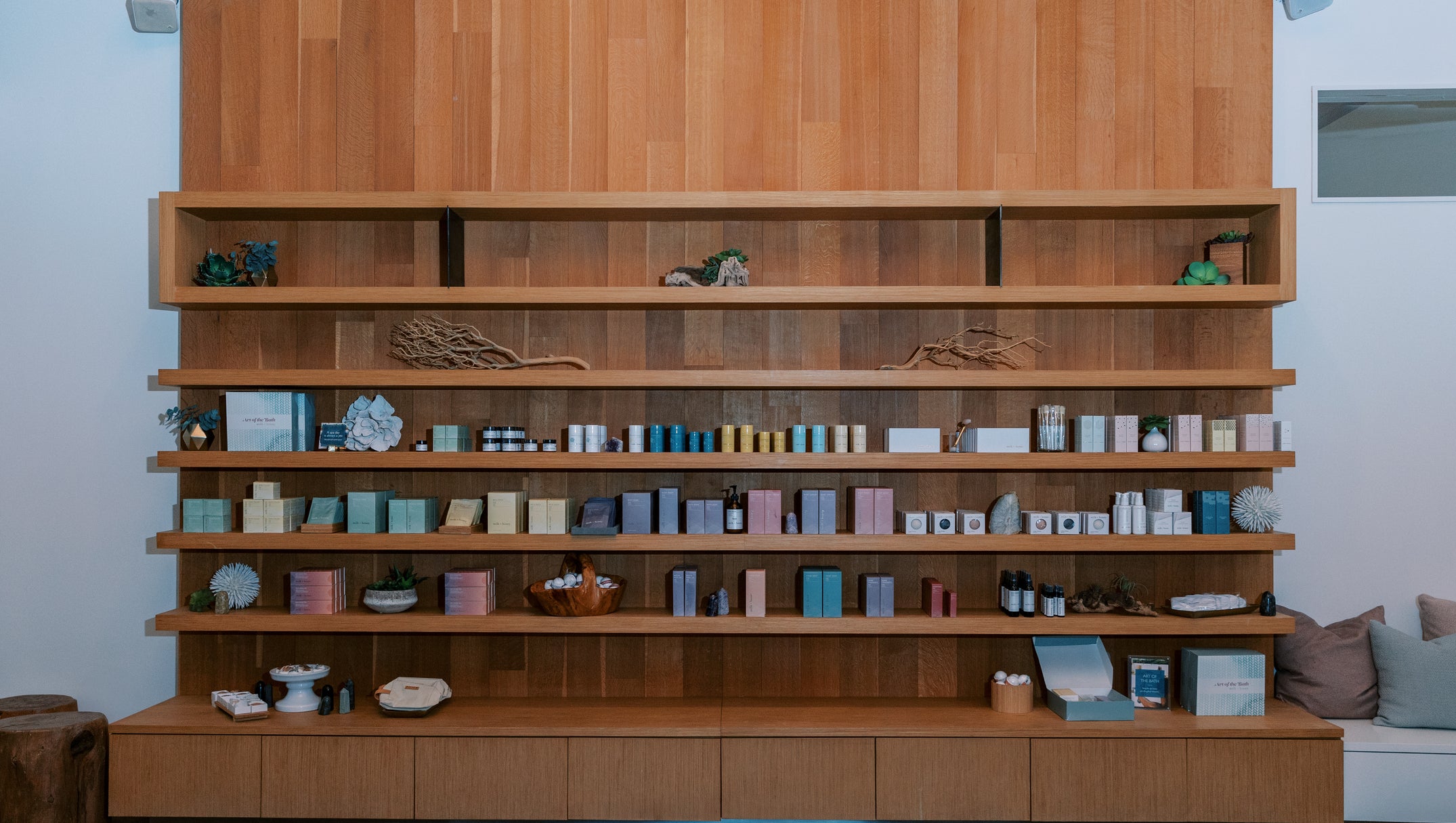 A large built-in wooden shelving unit with multiple tiers and a lower cabinet, displaying many small boxes, jars, and decorative objects in a home interior.