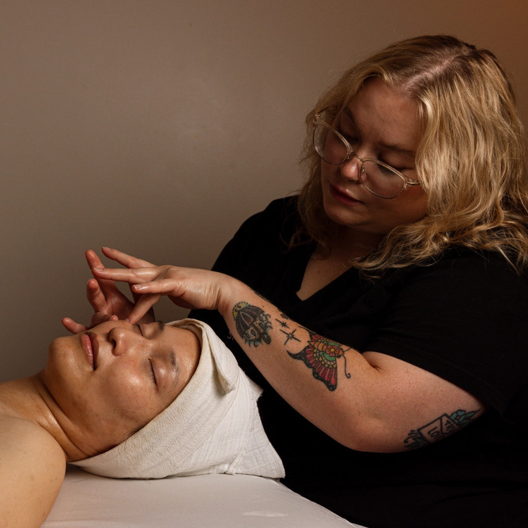 Person receiving a facial treatment from another person in a professional setting.