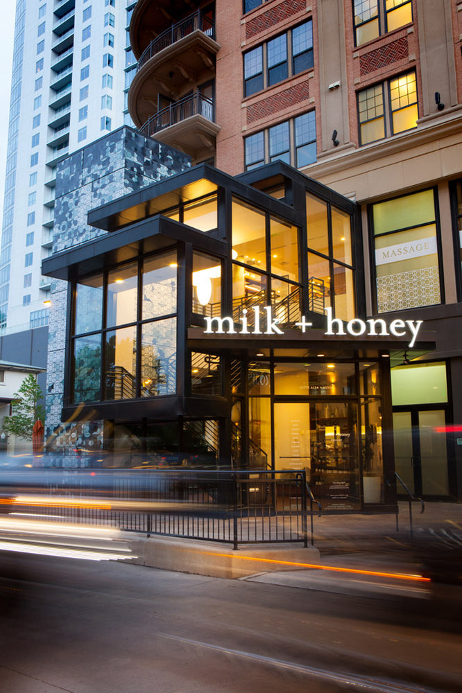 Modern building with 'milk + honey' sign on a city street