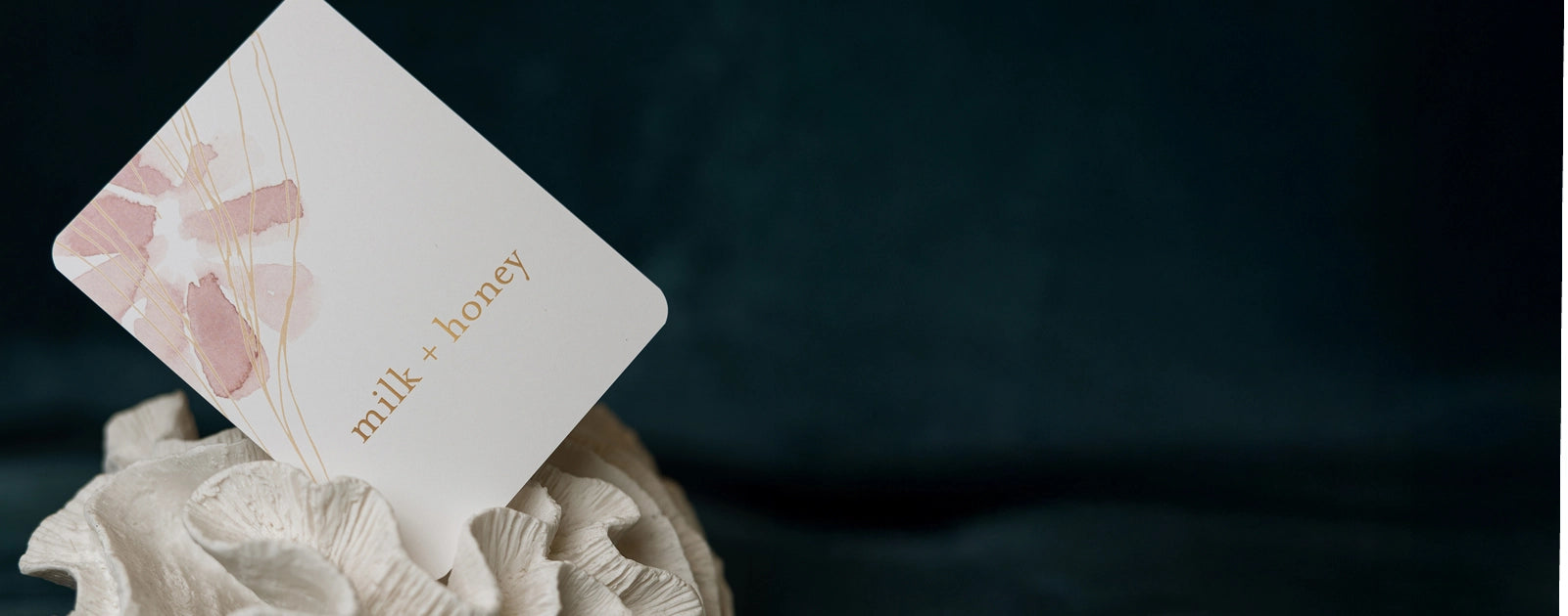 Card with 'milk honey' branding on a textured surface against a dark background