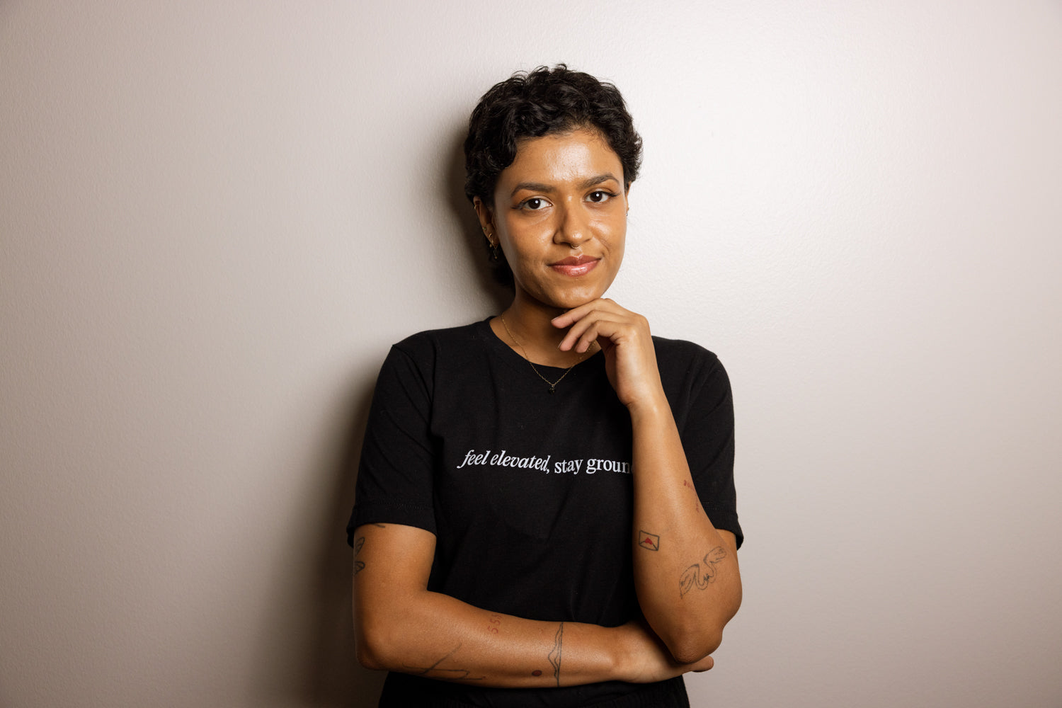 Person wearing a black t-shirt with text, standing against a plain background