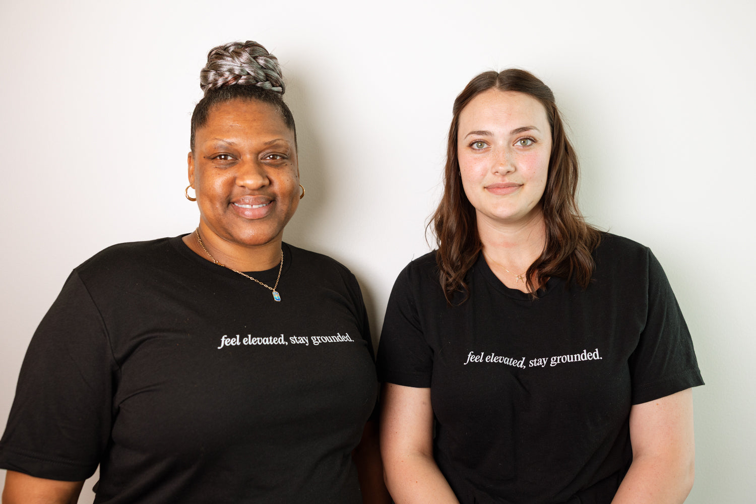 Two women wearing black t-shirts with text on a white background